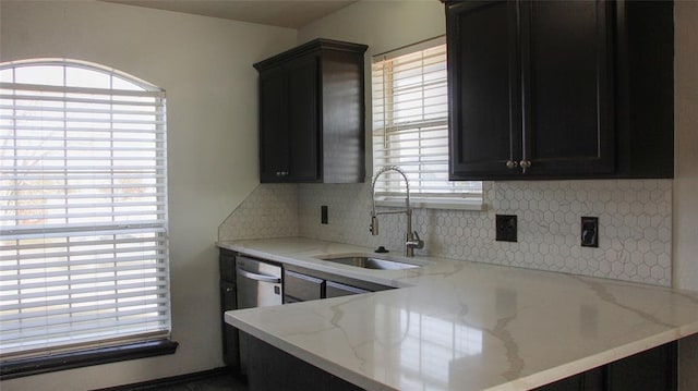 kitchen with backsplash, light stone counters, and sink