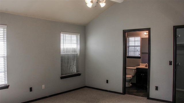 unfurnished bedroom with multiple windows, ensuite bathroom, ceiling fan, and light colored carpet