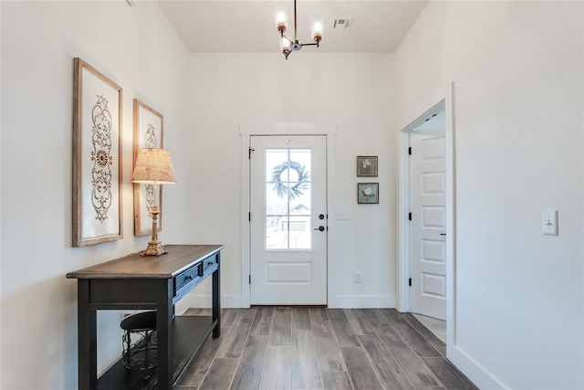 entryway with a notable chandelier, wood finished floors, visible vents, and baseboards