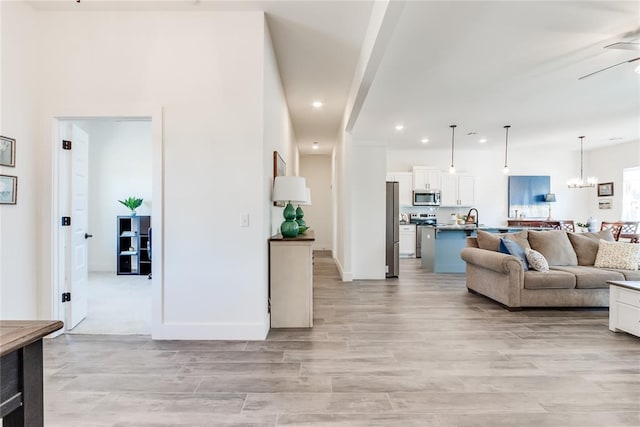 living area with baseboards, light wood-style floors, recessed lighting, and a notable chandelier