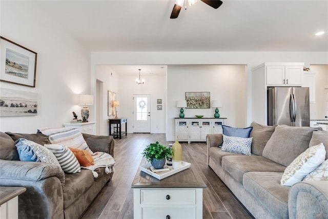 living area featuring dark wood-style flooring and ceiling fan with notable chandelier