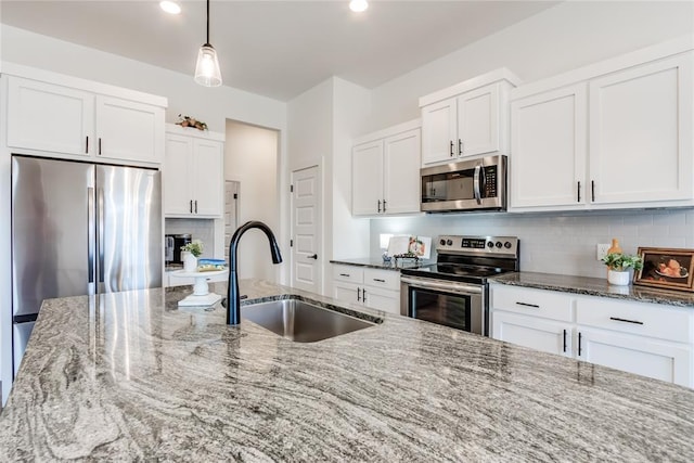 kitchen with tasteful backsplash, appliances with stainless steel finishes, white cabinets, and a sink