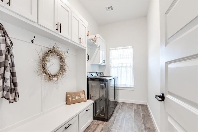 mudroom featuring light wood-style floors, visible vents, baseboards, and separate washer and dryer