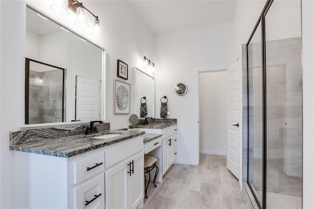 bathroom featuring a sink, a shower stall, baseboards, and double vanity