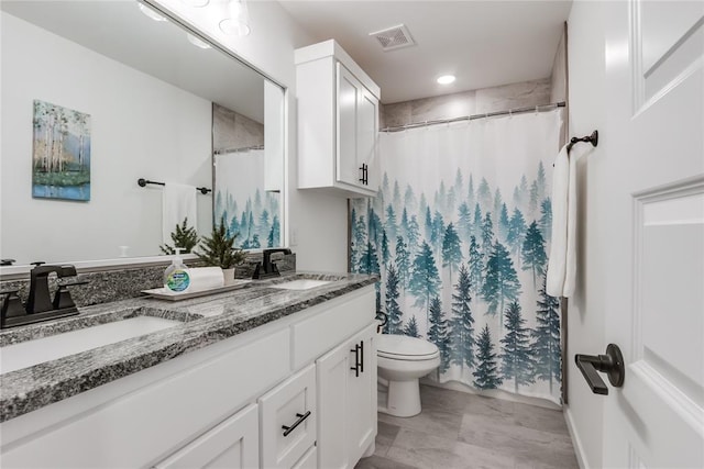 full bath featuring toilet, double vanity, visible vents, and a sink