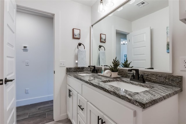 bathroom with double vanity, wood finished floors, a sink, and visible vents