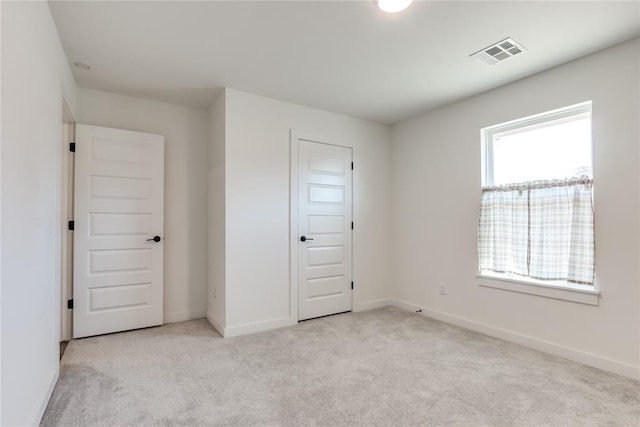 unfurnished room featuring light colored carpet, visible vents, and baseboards