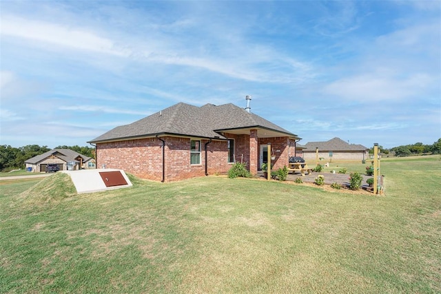 view of front of property featuring brick siding, a front lawn, and a shingled roof