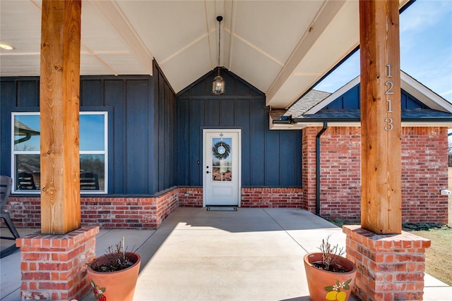 property entrance featuring board and batten siding and brick siding