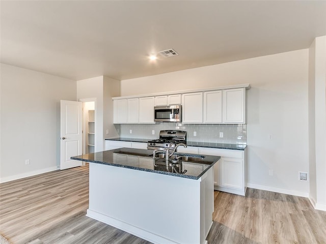13074 Mannington Rd, Edmond, OK 73025 - kitchen with appliances with stainless steel finishes, light wood-type flooring, dark stone counters, and decorative backsplash
