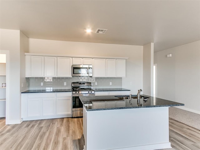 13074 Mannington Rd, Edmond, OK 73025 - kitchen featuring stainless steel appliances, light wood-type flooring, white cabinetry, and dark stone countertops