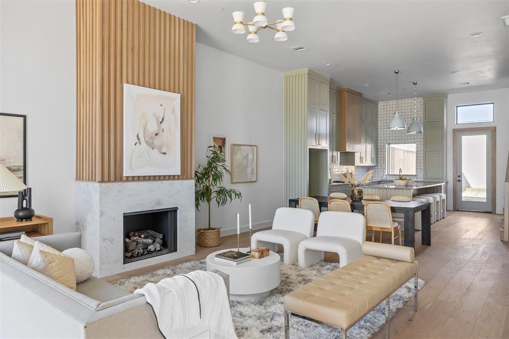 living room featuring a chandelier, light wood-type flooring, and a fireplace