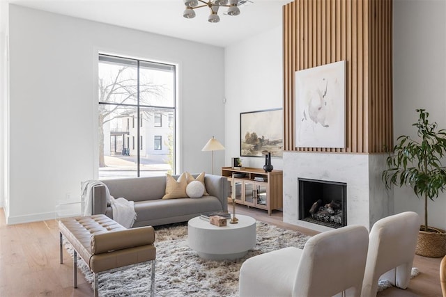 living room with a chandelier, light wood-type flooring, and a premium fireplace