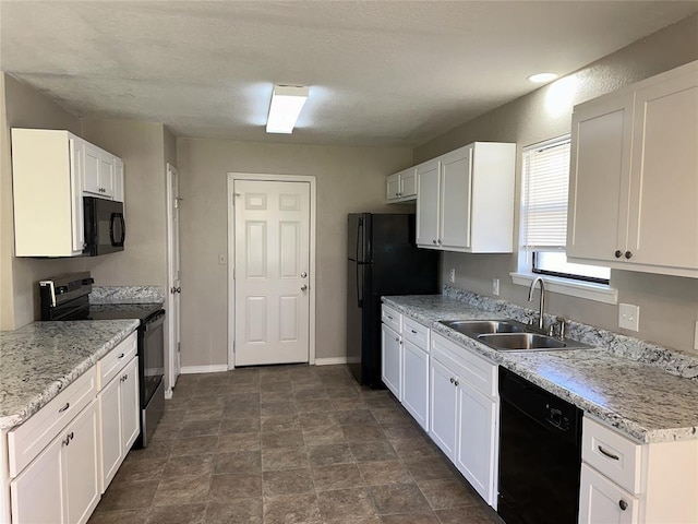 kitchen featuring black appliances, light stone counters, white cabinets, and sink