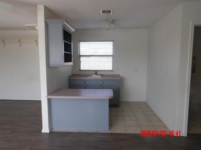 kitchen with tile patterned flooring, gray cabinets, kitchen peninsula, and sink