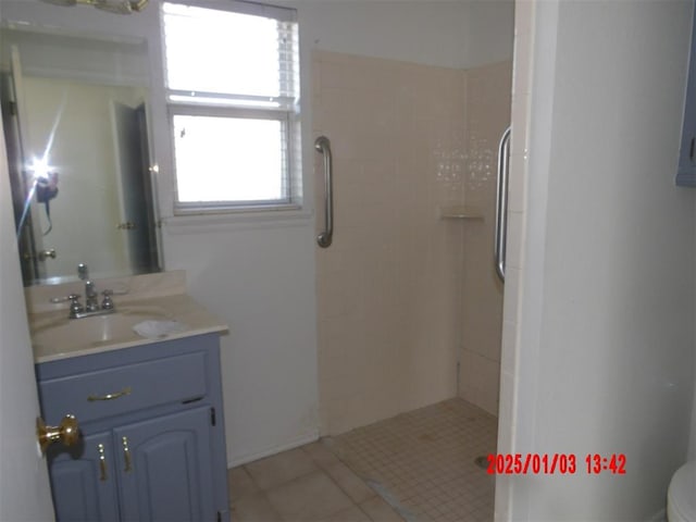 bathroom featuring a tile shower, vanity, and tile patterned floors