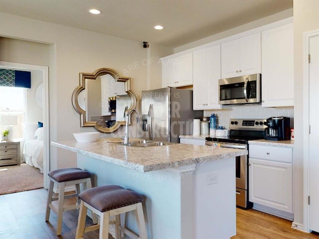 kitchen featuring white cabinetry, sink, stainless steel appliances, a breakfast bar area, and light wood-type flooring