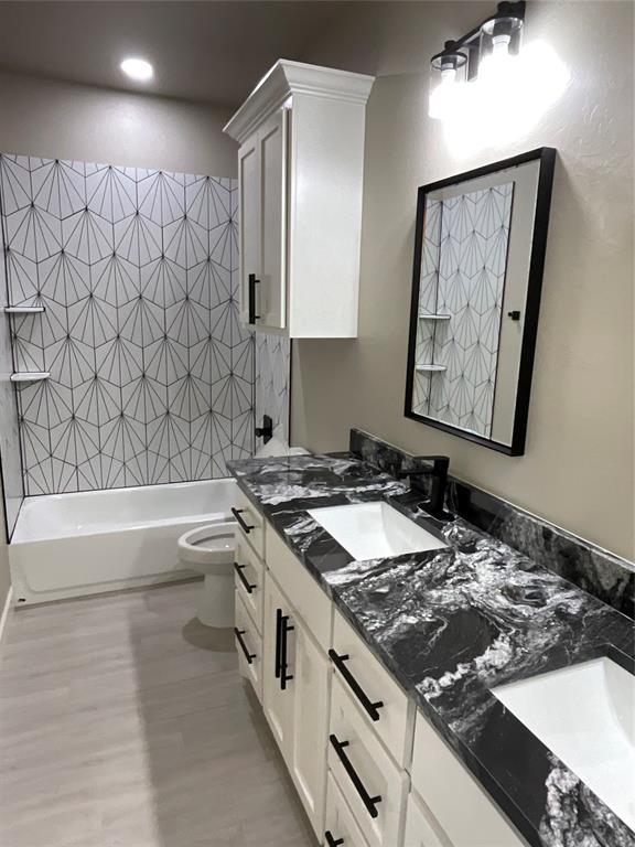 full bathroom featuring vanity, tiled shower / bath combo, wood-type flooring, and toilet