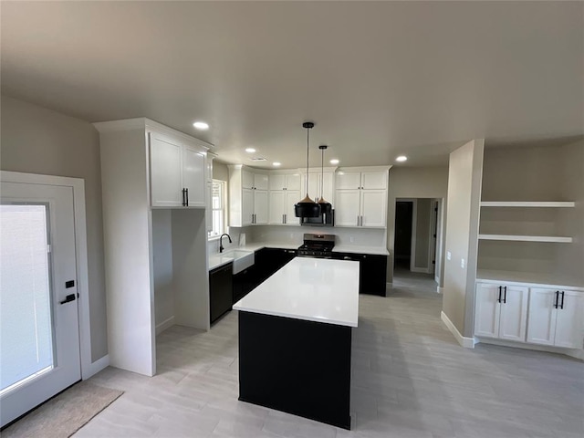 kitchen featuring a sink, light countertops, appliances with stainless steel finishes, white cabinetry, and a center island