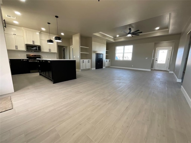 kitchen with visible vents, light wood-style flooring, a ceiling fan, appliances with stainless steel finishes, and a raised ceiling