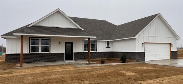 view of front facade with board and batten siding, concrete driveway, an attached garage, a shingled roof, and brick siding