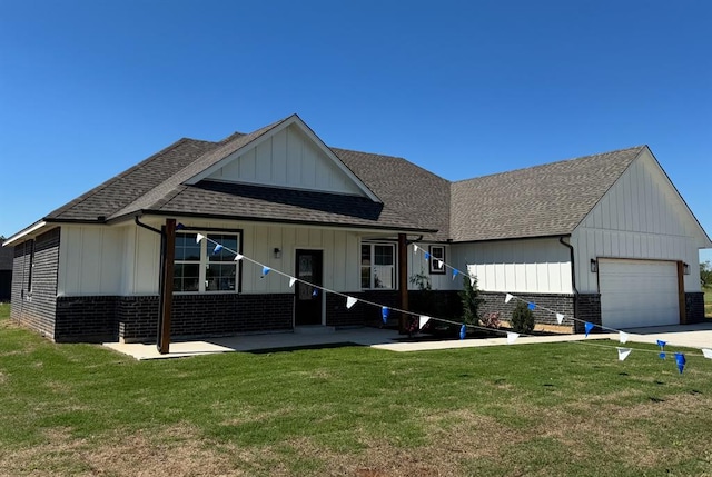 view of front of property featuring board and batten siding, a front yard, an attached garage, and roof with shingles