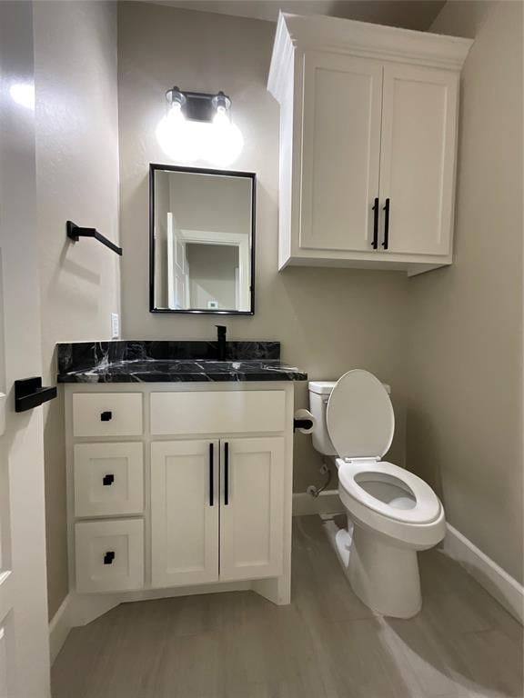 bathroom featuring toilet, baseboards, and vanity
