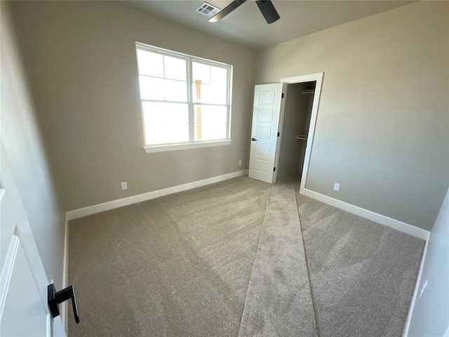 unfurnished bedroom with visible vents, carpet floors, baseboards, ceiling fan, and a spacious closet