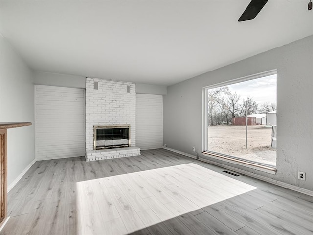 unfurnished living room with a fireplace, a healthy amount of sunlight, and light wood-type flooring