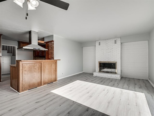 unfurnished living room with a fireplace, light wood-type flooring, and ceiling fan