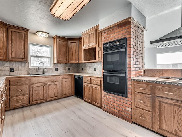 kitchen featuring ventilation hood, sink, light hardwood / wood-style flooring, double oven, and tasteful backsplash