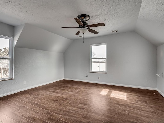 additional living space featuring lofted ceiling, a textured ceiling, and dark wood-type flooring