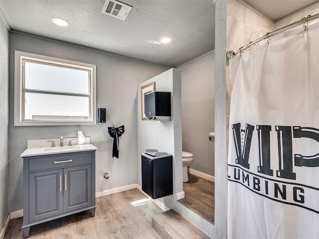 full bathroom with wood finished floors, vanity, a shower with curtain, baseboards, and visible vents