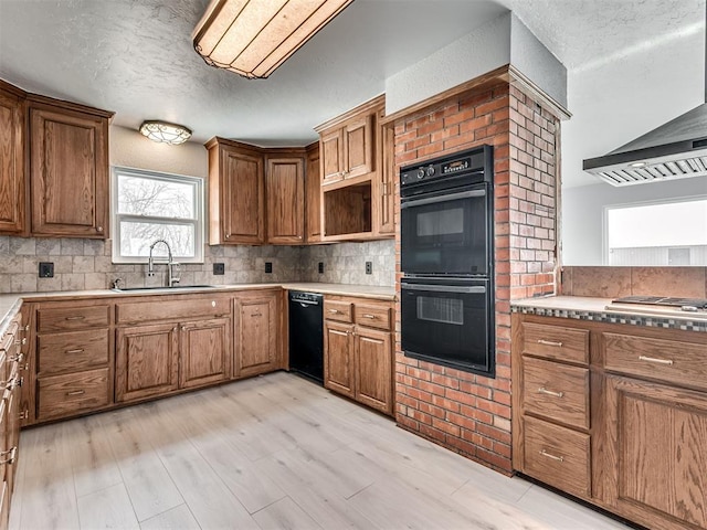 kitchen with backsplash, dobule oven black, wall chimney exhaust hood, and a sink