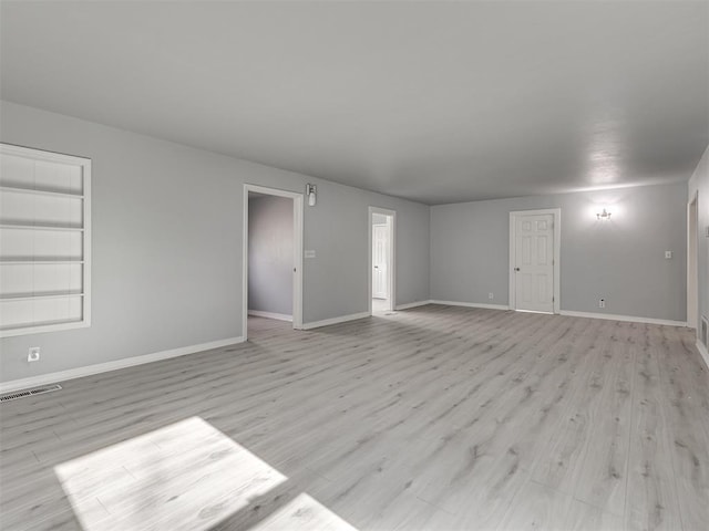 unfurnished living room with visible vents, light wood finished floors, and baseboards