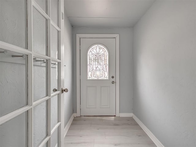 doorway to outside featuring baseboards and light wood-style floors