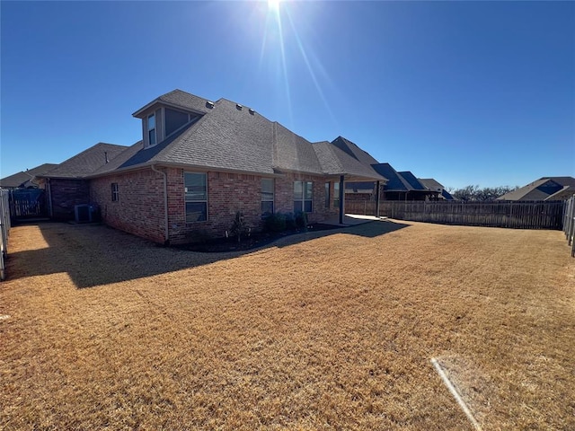 4309 NW 152nd Pl, Edmond, OK 73013 - rear view of property featuring a fenced backyard, brick siding, a lawn, a shingled roof, and cooling unit