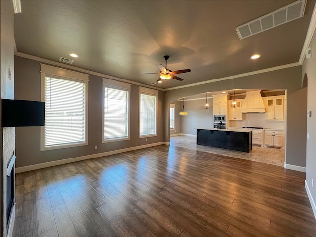 4309 NW 152nd Pl, Edmond, OK 73013 - unfurnished living room featuring wood finished floors, visible vents, arched walkways, ceiling fan, and ornamental molding