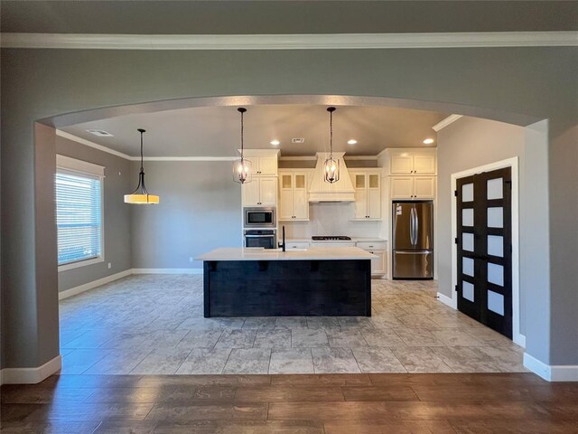 4309 NW 152nd Pl, Edmond, OK 73013 - kitchen featuring arched walkways, light countertops, premium range hood, and appliances with stainless steel finishes