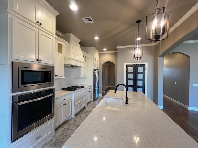 4309 NW 152nd Pl, Edmond, OK 73013 - kitchen with french doors, a sink, custom exhaust hood, stainless steel appliances, and arched walkways