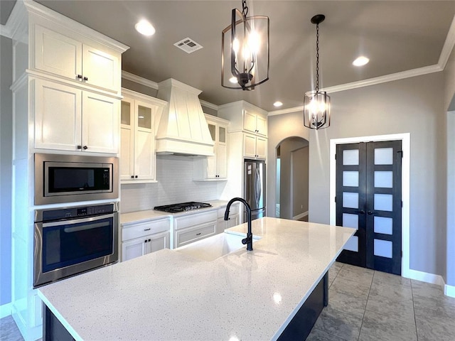 4309 NW 152nd Pl, Edmond, OK 73013 - kitchen featuring custom range hood, backsplash, a sink, arched walkways, and appliances with stainless steel finishes