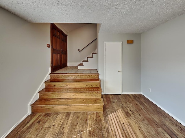 stairs with wood-type flooring and a textured ceiling