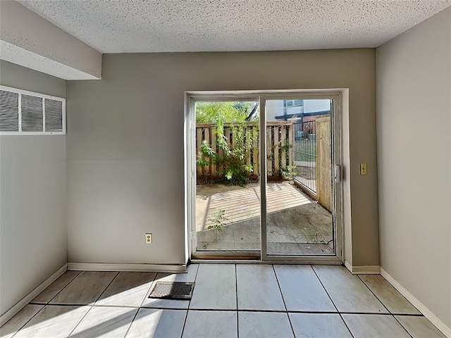 doorway to outside featuring light tile patterned flooring and a textured ceiling