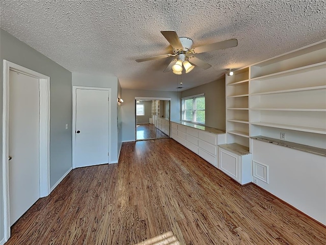 unfurnished living room with a textured ceiling, ceiling fan, and dark wood-type flooring