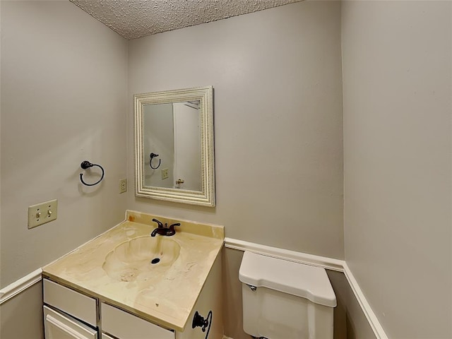 bathroom with vanity, toilet, and a textured ceiling