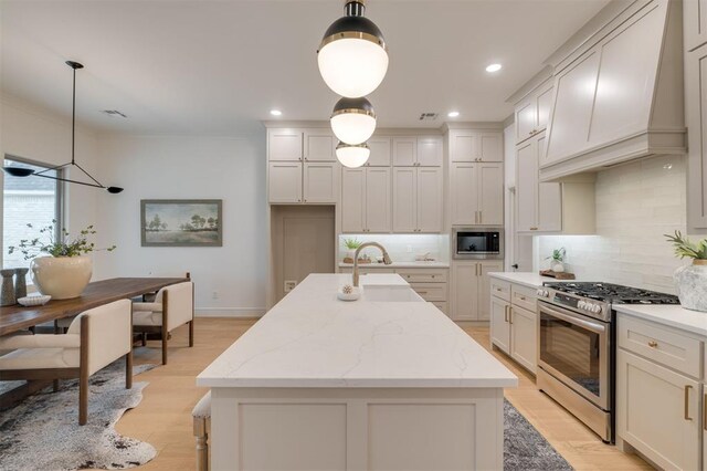 kitchen featuring gas stove, built in microwave, and a kitchen island with sink