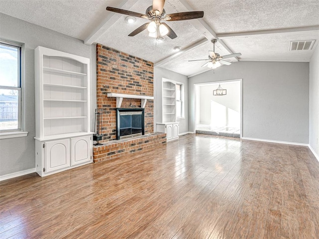 unfurnished living room featuring a textured ceiling, ceiling fan, lofted ceiling with beams, built in features, and a fireplace