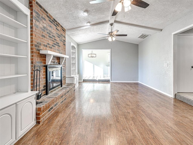 unfurnished living room with built in shelves, a fireplace, a textured ceiling, and vaulted ceiling with beams