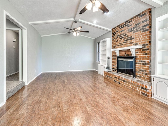 unfurnished living room featuring ceiling fan, vaulted ceiling with beams, built in features, a textured ceiling, and a fireplace