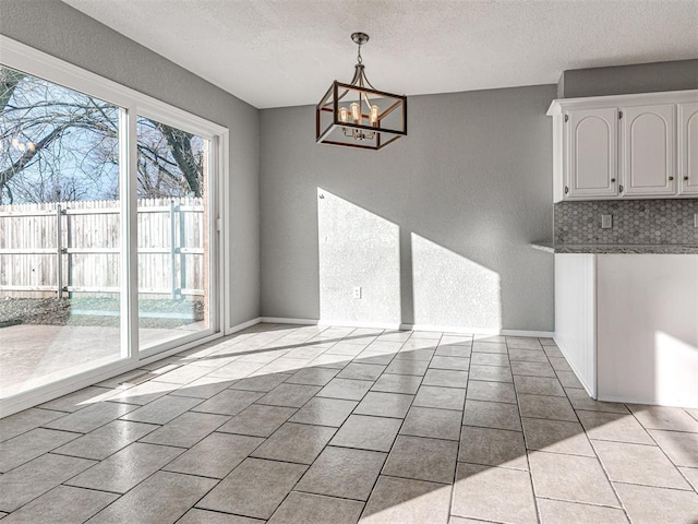 unfurnished dining area featuring a chandelier, light tile patterned floors, and a textured ceiling